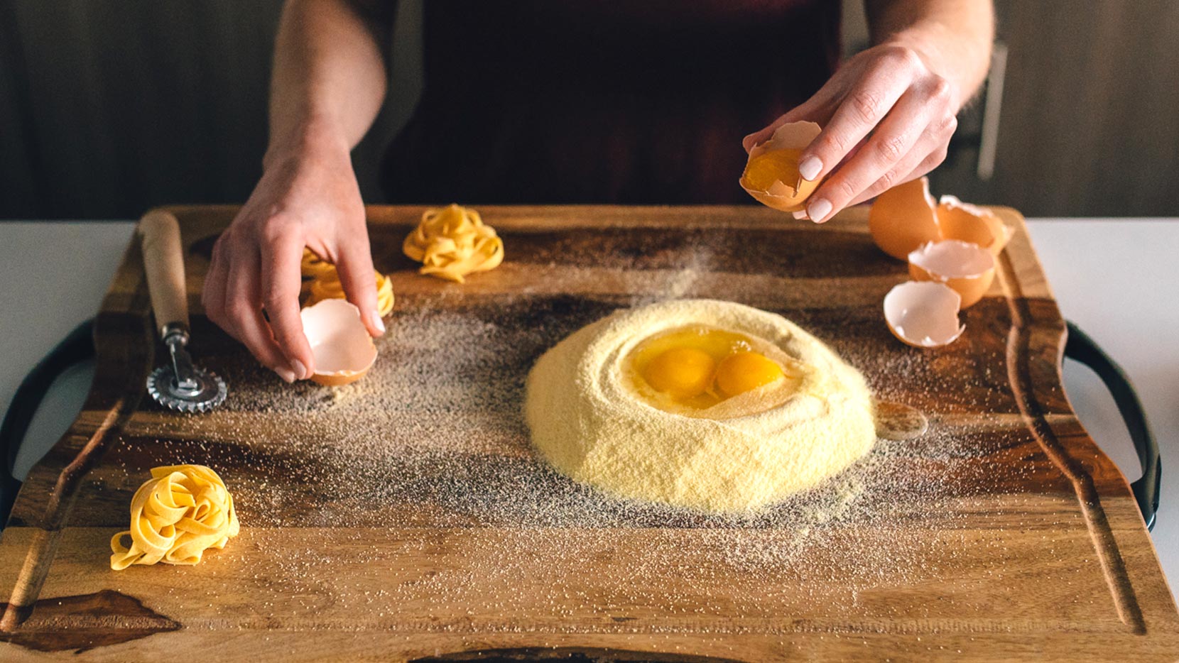 Combine all purpose and semolina flour into a cone, and press down the center. Then crack the eggs into the depression. 